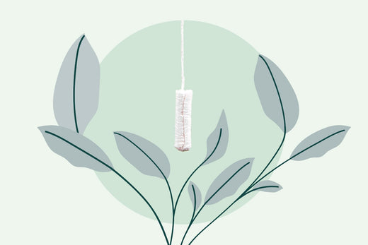 Tampon hanging in the center of the image with a green plant enveloping it.